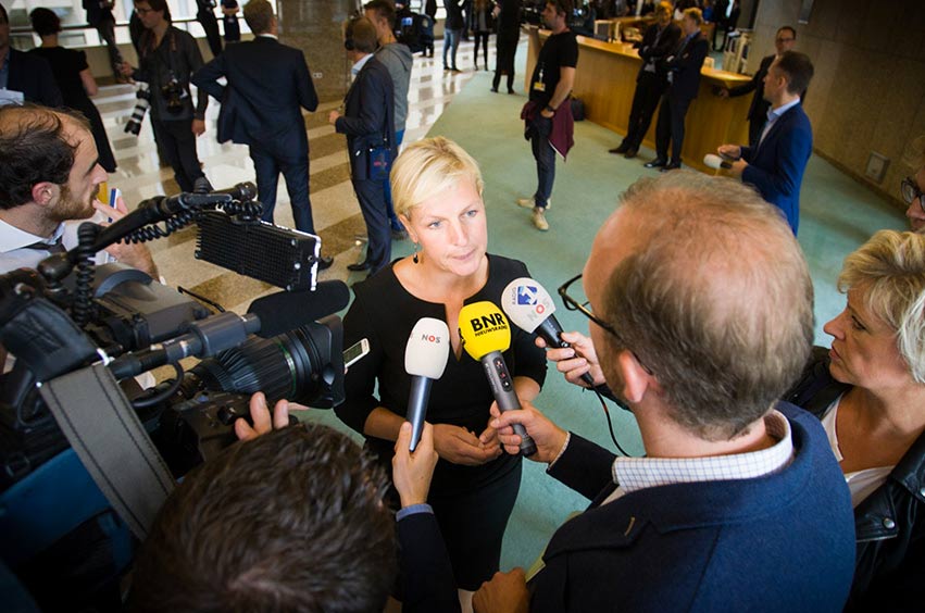 Media performance by an MP in the corridors of the House of Representatives. In front of microphones from BNR Nieuwsradio, NOS and Radio 1.