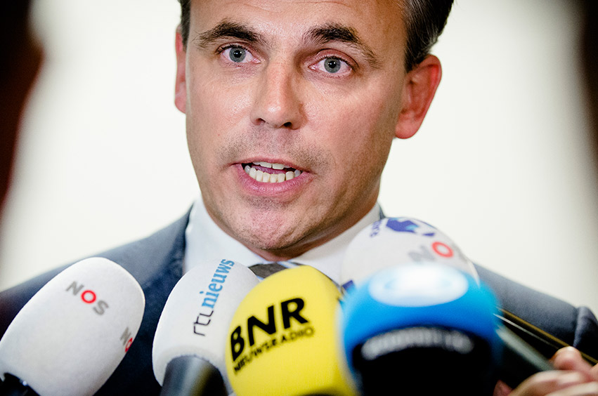 Politician talks to the media. In front of microphones from NOS, RTL and BNR.