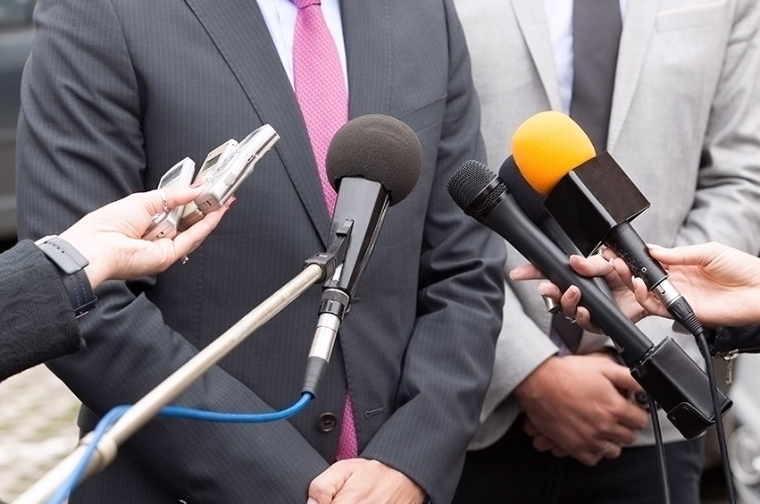 Man in a suit makes a statement to journalists.